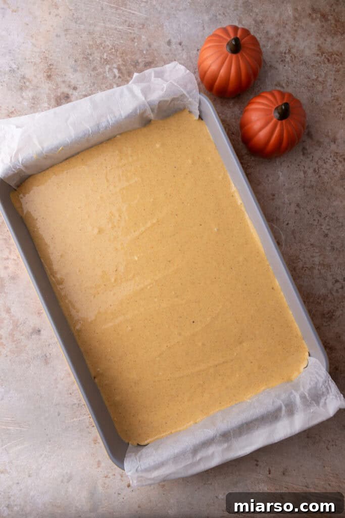 Pumpkin cheesecake filling being poured over the croissant dough base