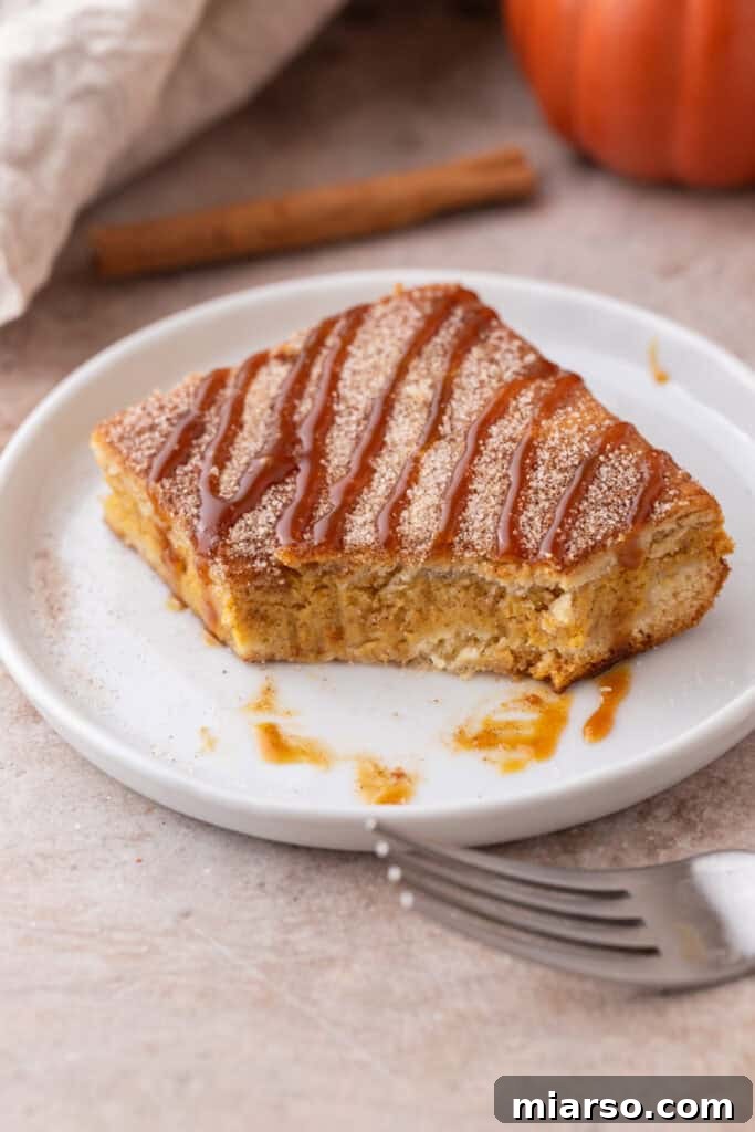 Churro Pumpkin cheesecake bars on a plate with a bite taken out, showing the layers