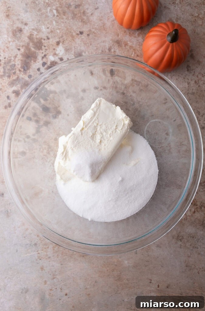 Cream cheese and sugar being beaten in a bowl