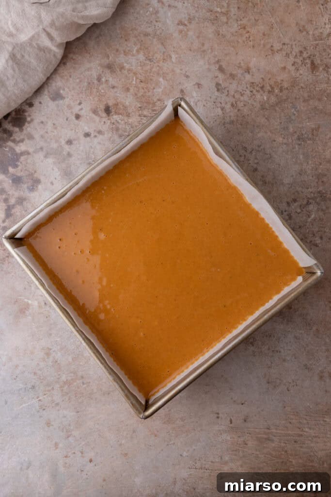 The smooth, raw sweet potato filling carefully poured over the baked shortbread crust in the pan, ready for its final bake.