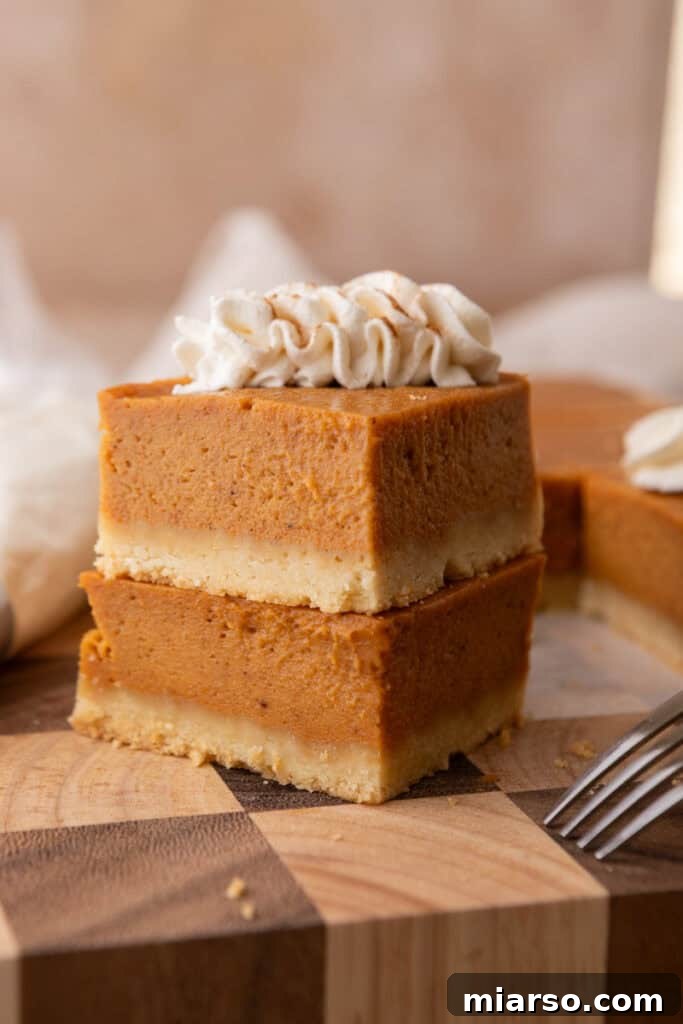A beautiful stack of freshly baked sweet potato pie bars, showcasing their distinct layers and inviting texture on a white plate.