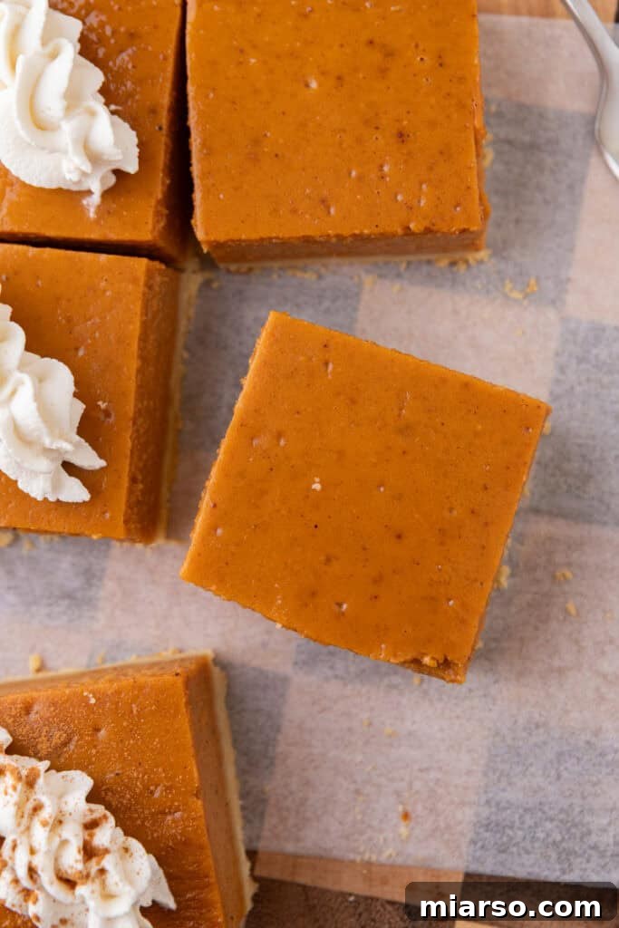 Sweet potato pie bars perfectly cut into even squares, neatly arranged on a white cutting board, ready for serving.