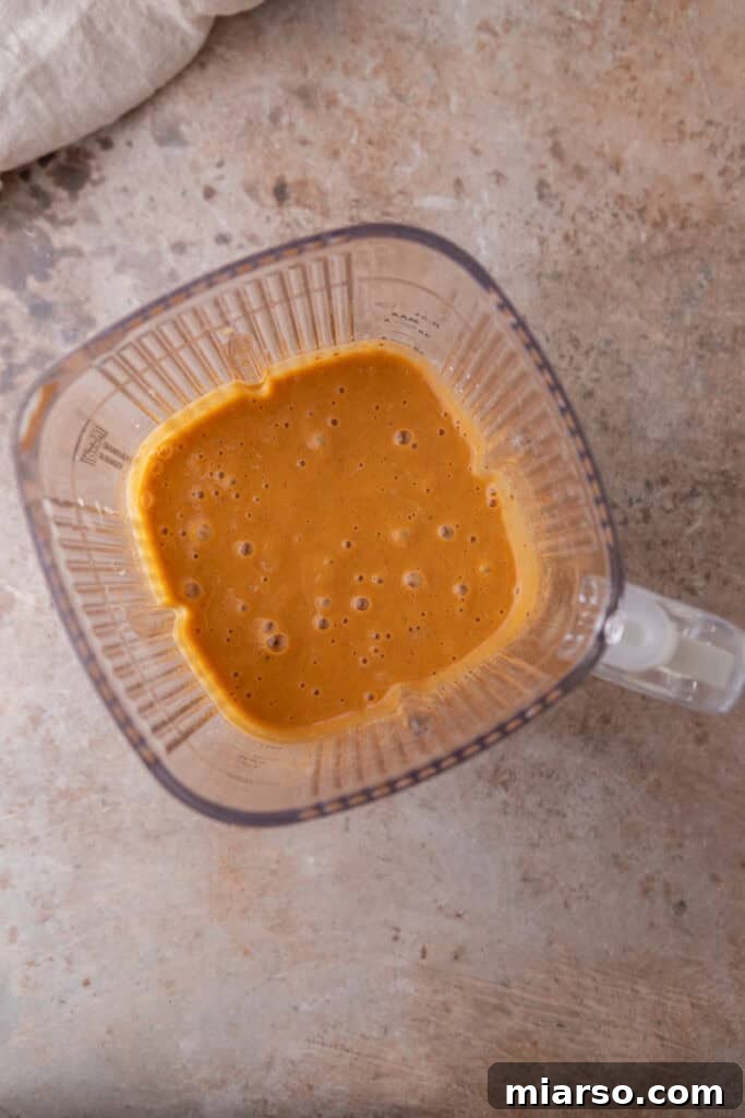 The beautifully smooth sweet potato filling mixture in a blender, now with the eggs incorporated, showing its creamy texture.