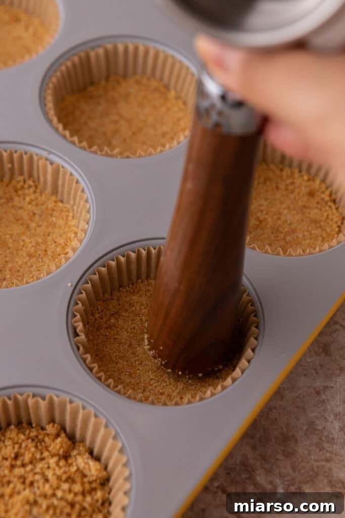 Each portion of the crust is firmly pressed down into the muffin liner, creating a solid and even base.