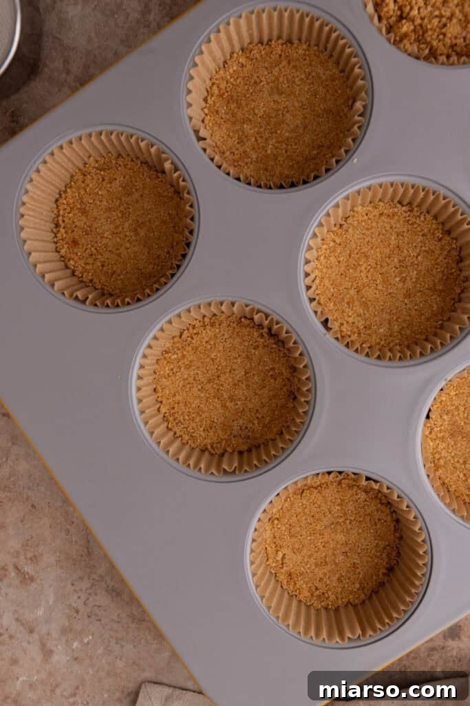 The prepared crusts are perfectly baked and cooling in the muffin tin, ready for the cheesecake filling.