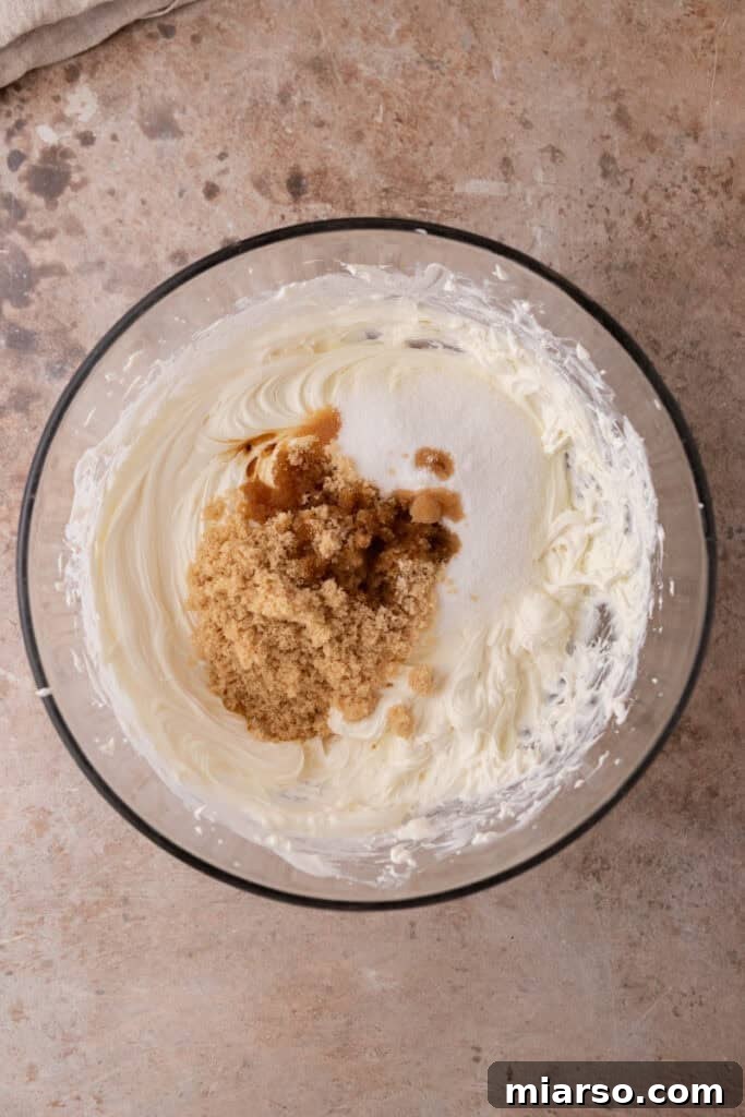 Sugars, salt, and vanilla extract are added to the cream cheese mixture and blended until fully incorporated.