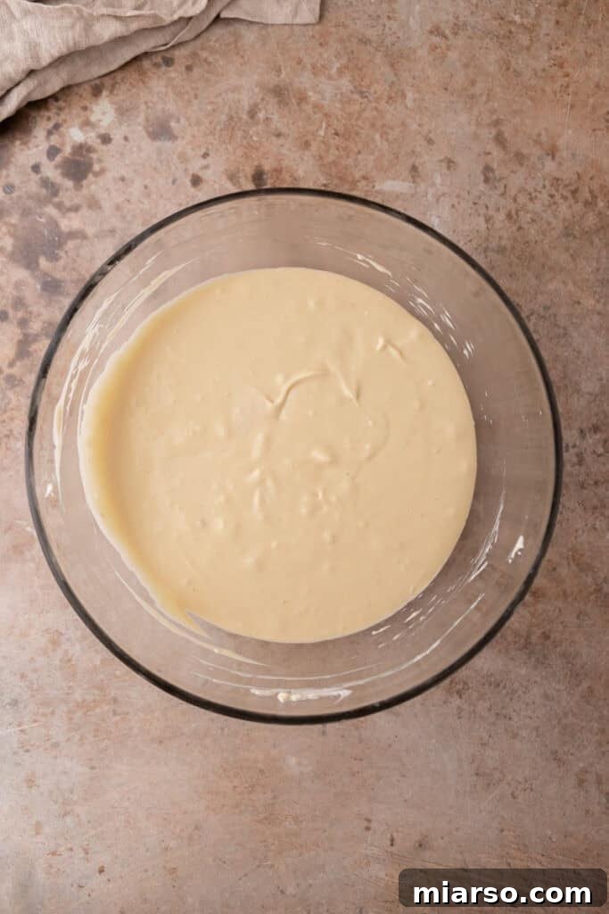 The fully mixed cheesecake filling, smooth and ready to be poured into the prepared crusts.