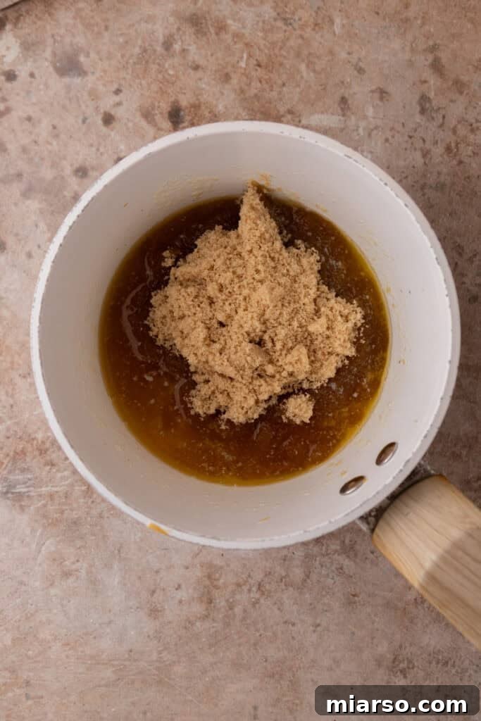 Brown sugar is added to the melted butter and whisked until smooth and bubbling, creating a rich caramel base.