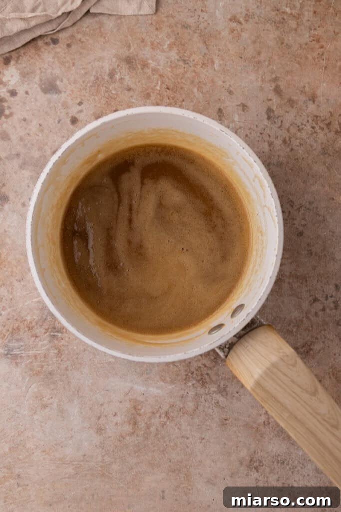 Heavy cream, corn syrup, and salt are stirred into the caramel mixture, forming a smooth and luxurious pecan topping base.
