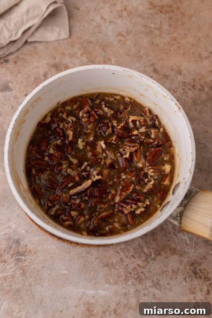 Vanilla extract is stirred into the pecan topping mixture, enhancing its aroma and overall taste.