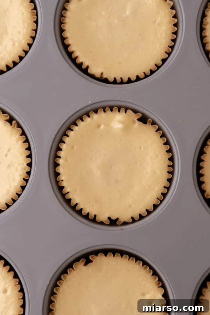 Mini Pecan Pie Cheesecakes beautifully topped with rich pecan pie filling, still in their muffin tin liners.