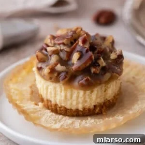 A delicious Mini Pecan Pie Cheesecake resting on an opened muffin liner, highlighting its individual serving size and appealing presentation.