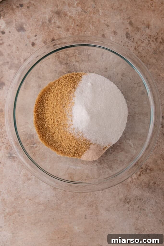 Graham cracker crumbs, sugar, and salt are mixed in a bowl, preparing for the crust of the mini cheesecakes.