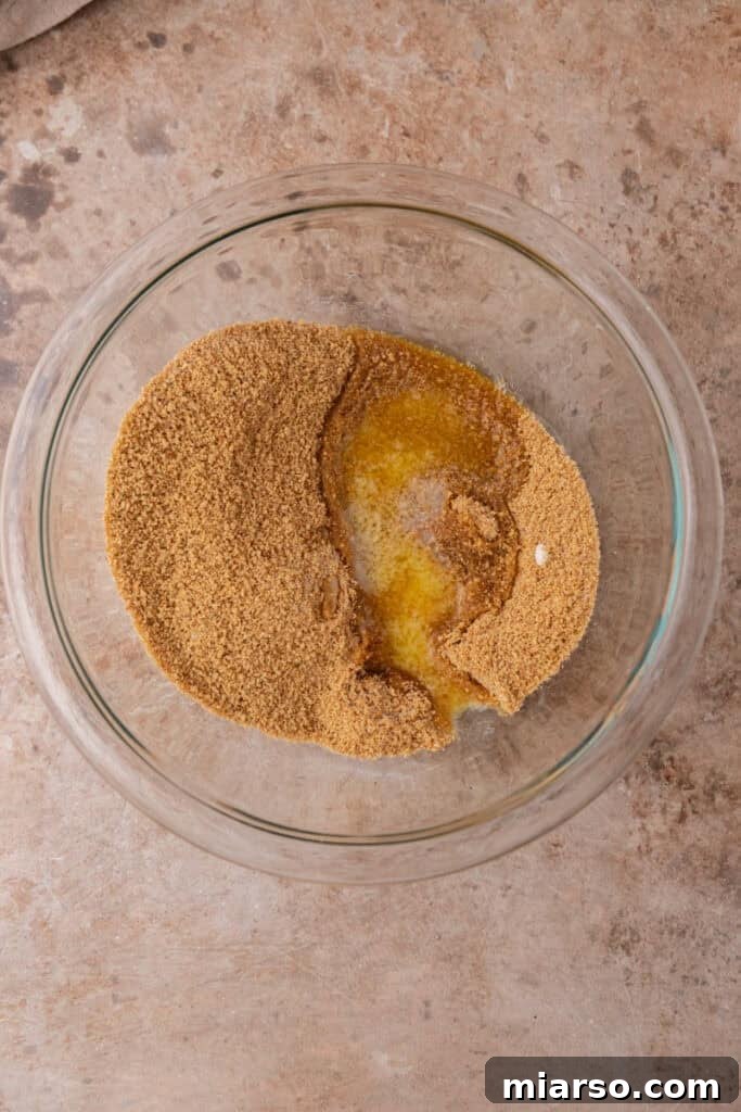 Melted butter is added to the dry graham cracker mixture, ensuring a rich and cohesive crust.