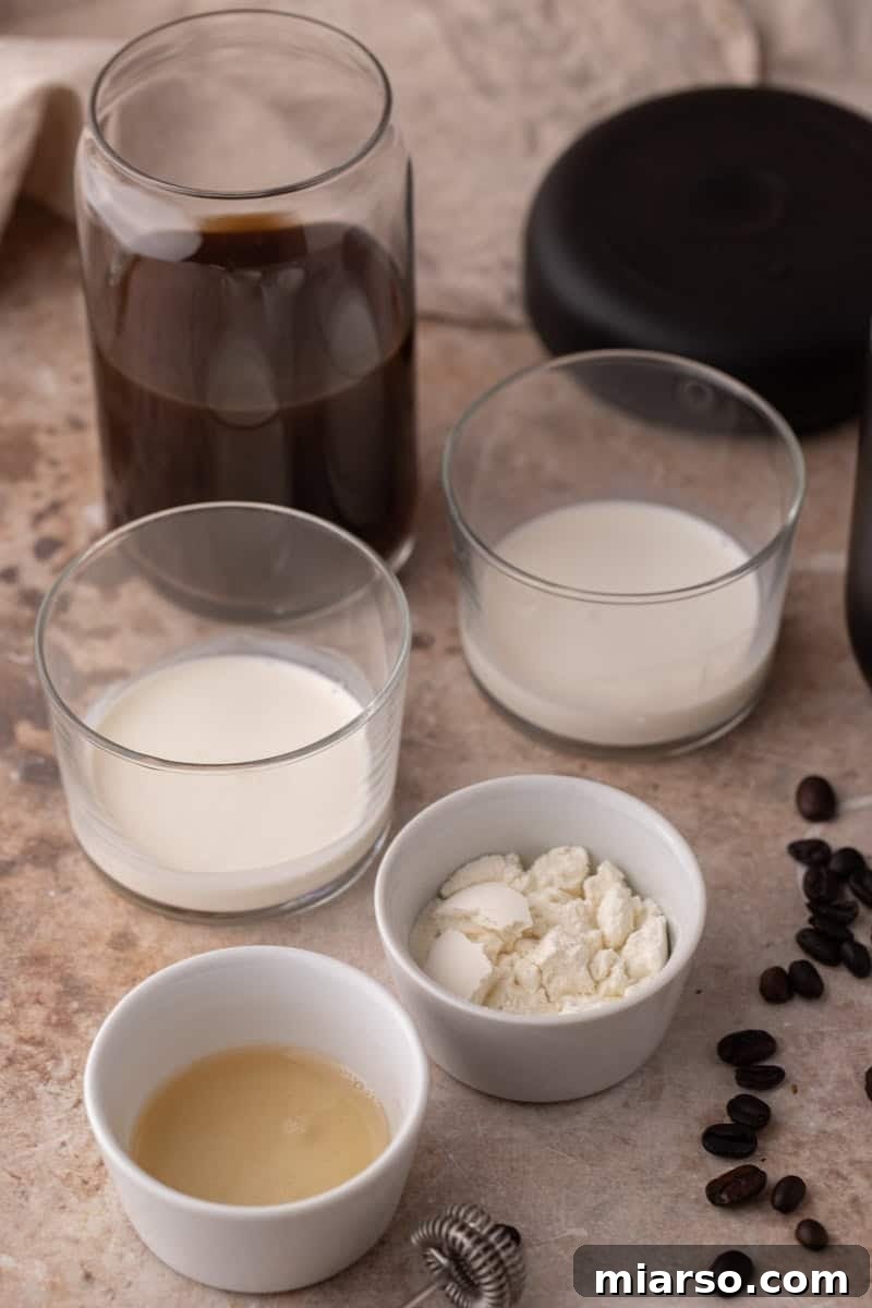 Starbucks Inspired High Protein Cold Foam 3 A collection of ingredients on a kitchen counter, including a bottle of cold brew, heavy cream, milk, vanilla syrup, and a scoop of whey protein powder, ready for mixing.