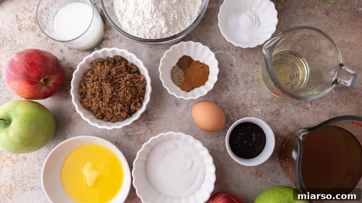 Ingredients for baked apple cider donuts, including reduced apple cider, flour, spices, sugars, egg, and butter arranged on a countertop.