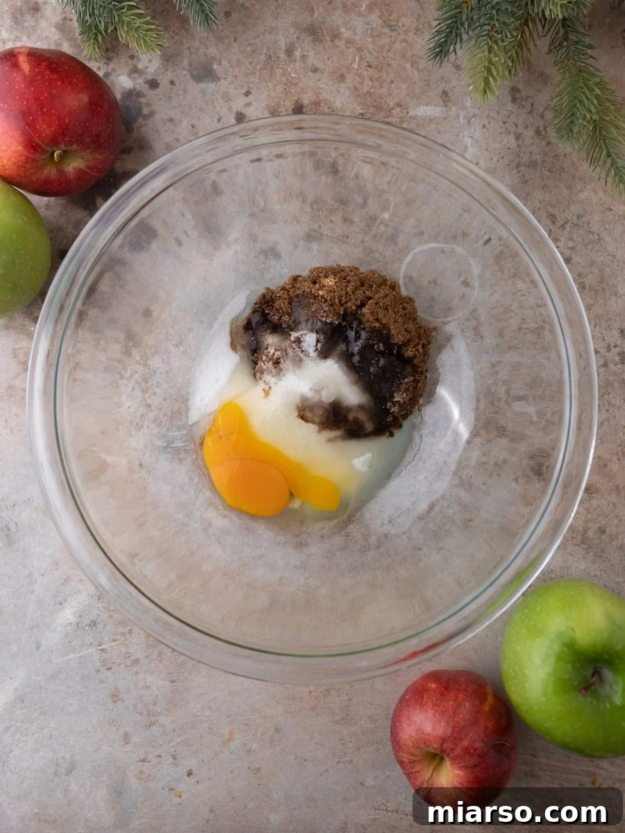 Brown sugar, granulated sugar, and egg combined in a mixing bowl for apple cider donut batter.