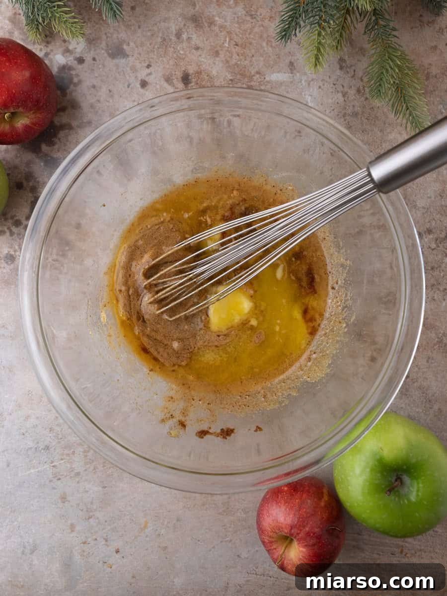 Whisking melted butter into sugar mixture while making baked apple cider donut batter.