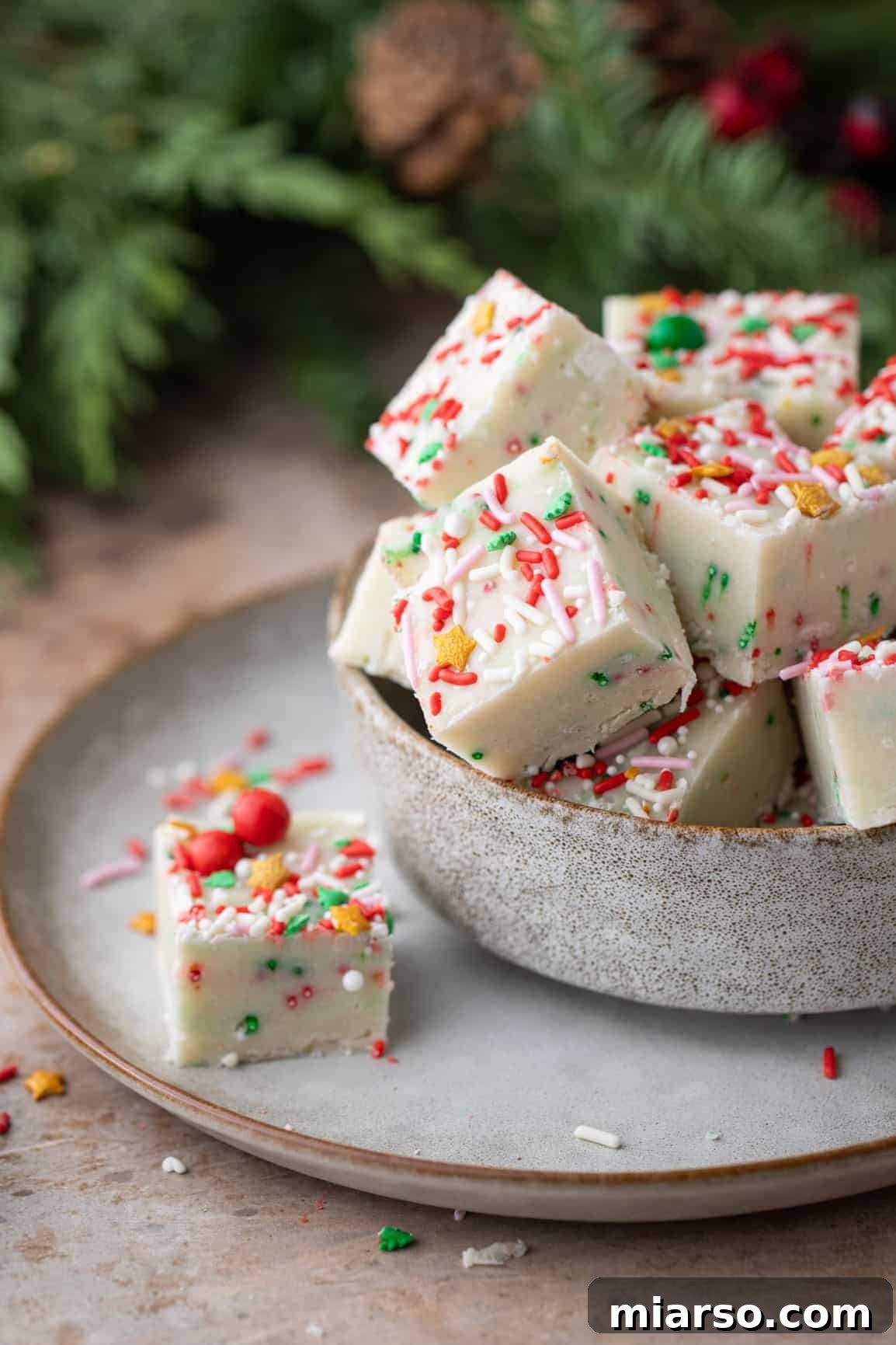 A bowl of festive sugar cookie fudge squares, with one square showcased separately adorned with sprinkles.
