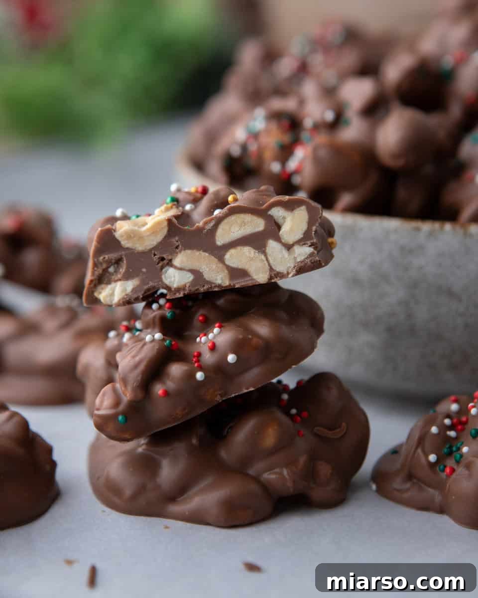 Effortless Slow Cooker Chocolate Peanut Clusters 10 A perfectly stacked arrangement of crockpot candy clusters, with one cluster expertly cut open to reveal the generous distribution of peanuts inside.