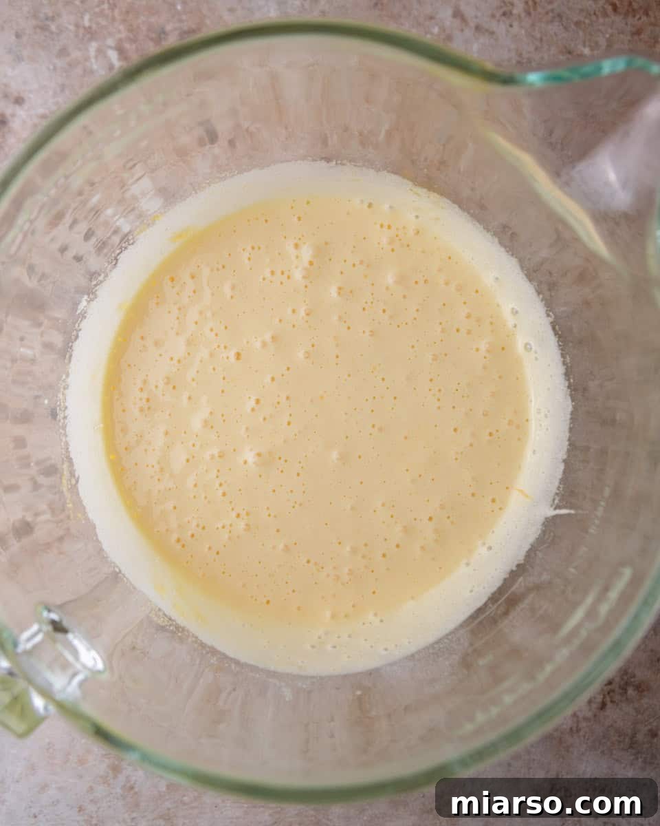 Ina Garten's Viral Brownie Pudding Sensation 5 The egg and sugar mixture after being whipped for several minutes, showing a pale yellow, thick, and airy consistency.