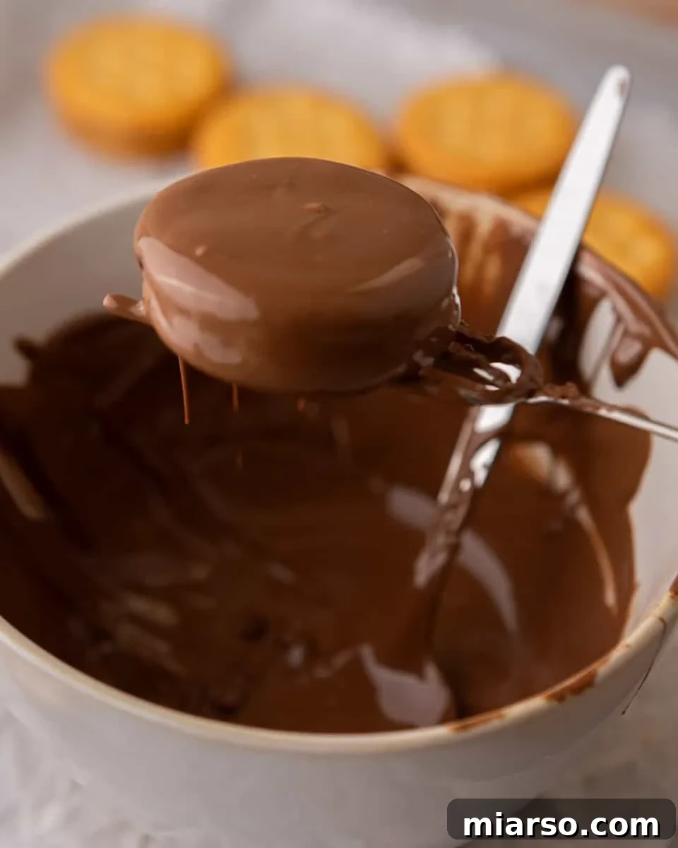 Ritz peanut butter cookies being dipped into melted milk chocolate