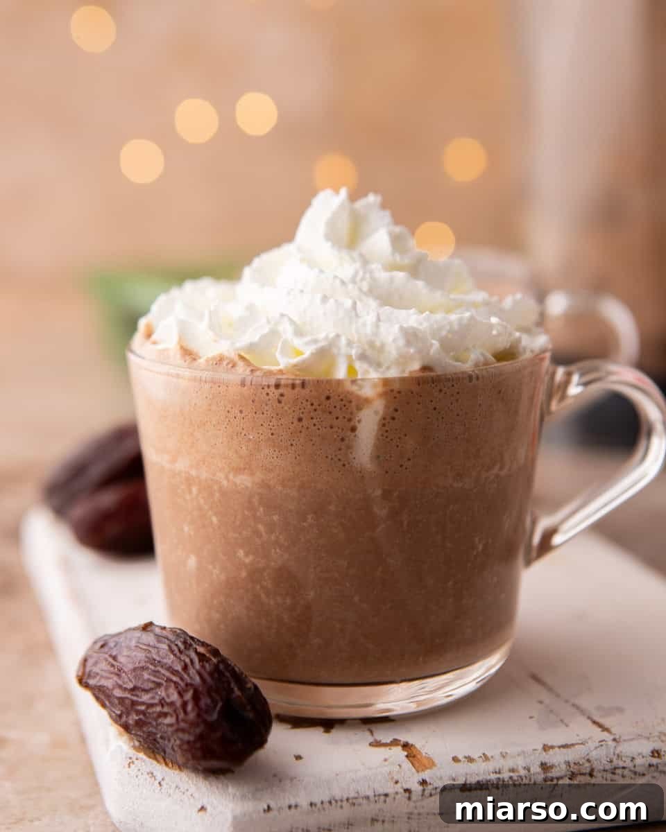 Date sweetened hot chocolate topped with whipped cream in a clear mug
