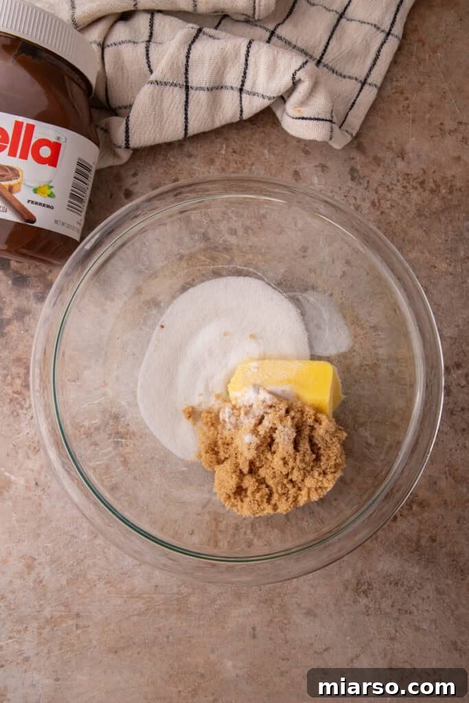 Ingredients for Nutella stuffed cookies including Nutella, butter, flour, egg, sugar, and chocolate chips