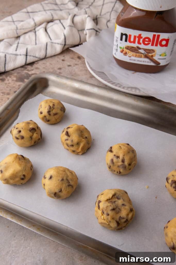 Nutella-filled chocolate chip cookie dough balls on baking sheet