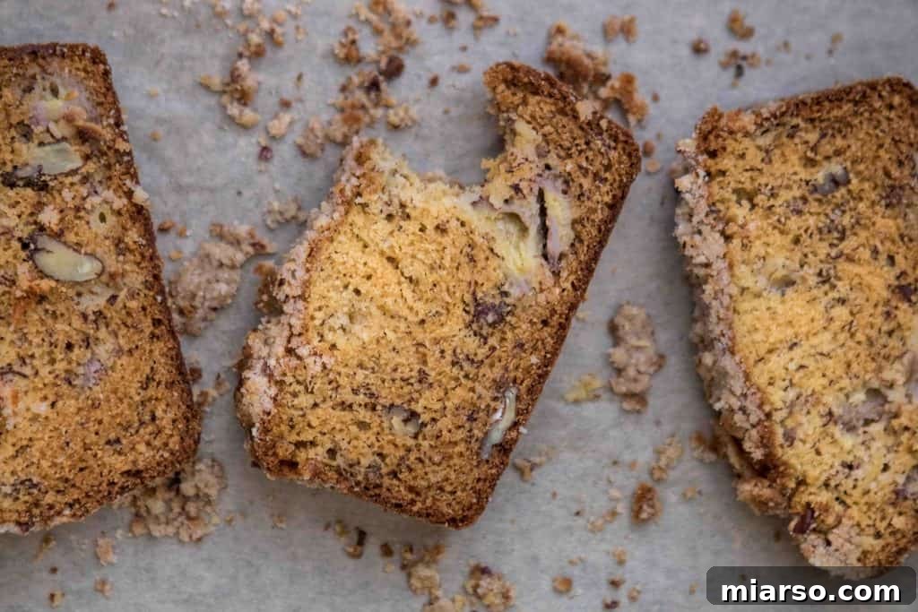 Slices of moist banana bread layered with pecans, showing the texture of the bread