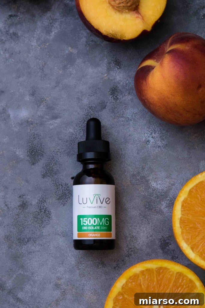 Citrus Peach CBD Serenity Smoothie 3 Dropper bottle of orange Luvive CBD oil next to fresh peaches, ready for smoothie preparation