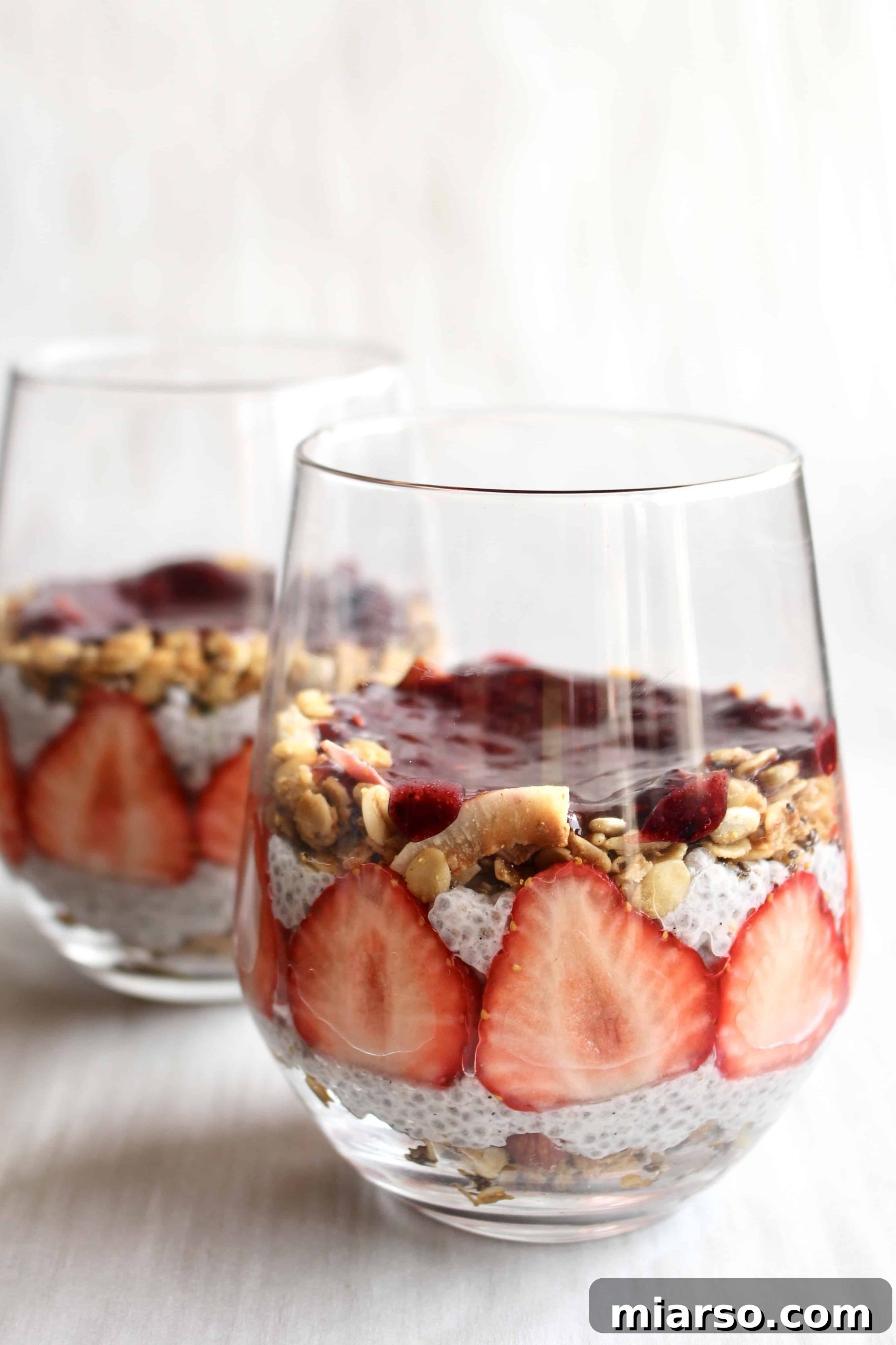 Layers of vibrant berry puree and creamy chia pudding beautifully separated in a glass, showcasing a well-assembled parfait