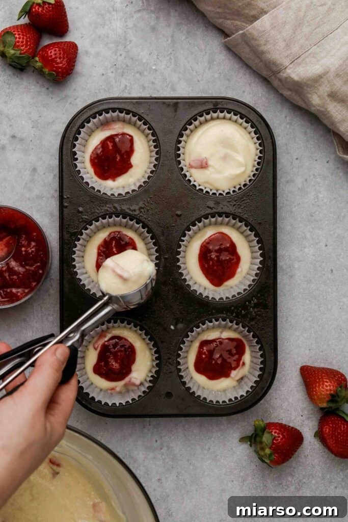 Another image of strawberry jam being placed in muffin center