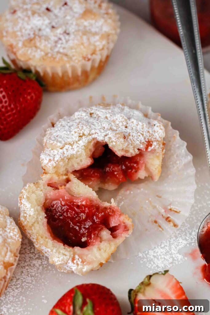 Close-up of jam oozing from the center of a streusel-topped strawberry muffin