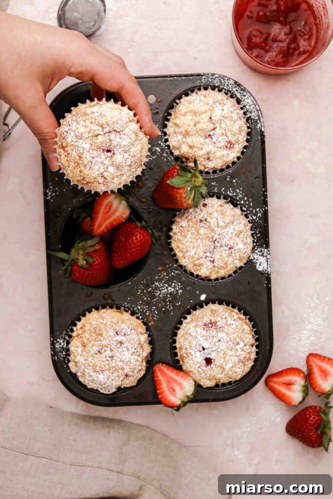 Hand reaching for a perfectly baked streusel strawberry muffin