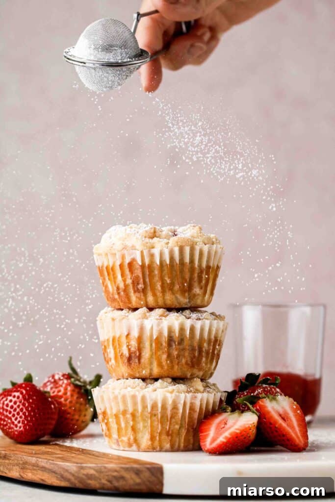 A stack of golden brown strawberry muffins, showcasing their streusel topping
