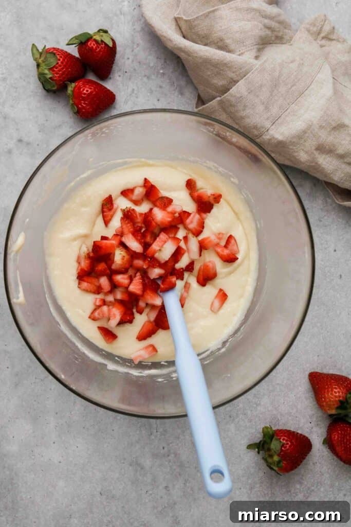 Folding fresh strawberries into the muffin batter