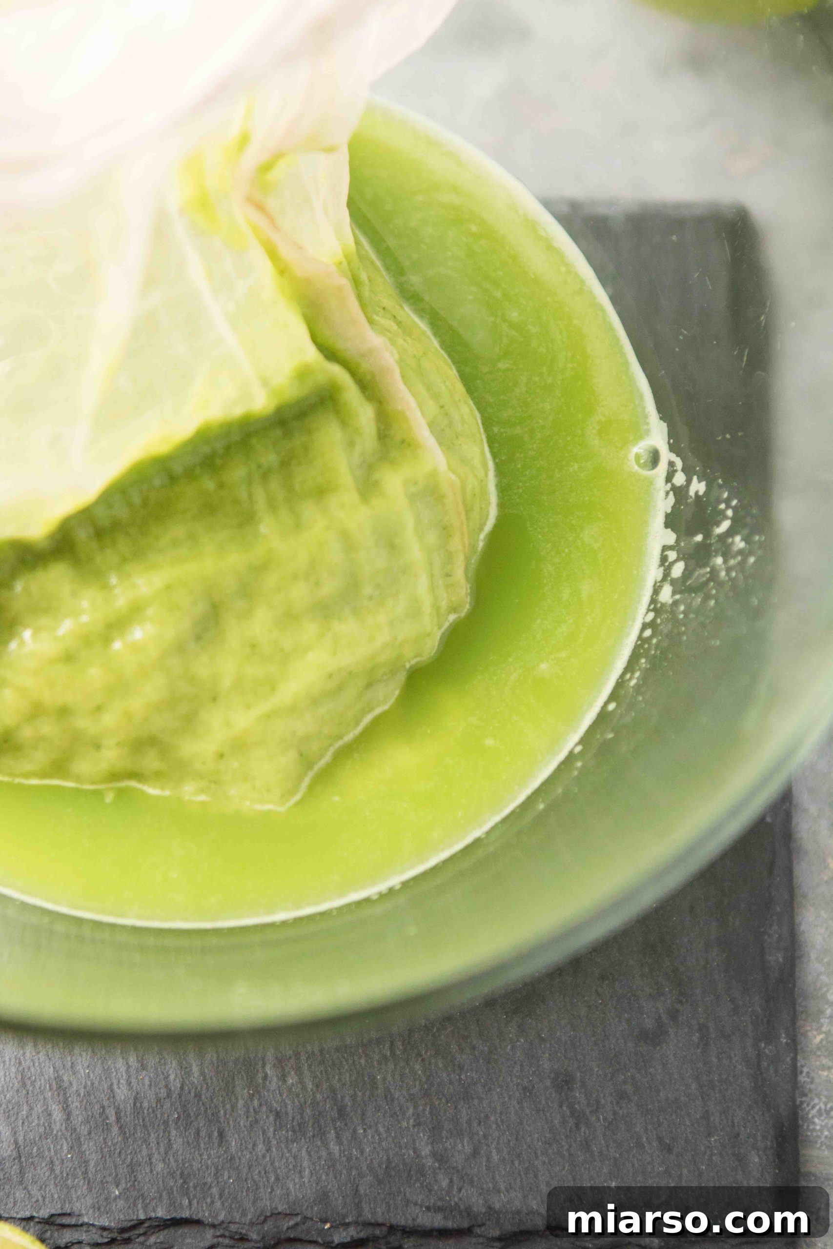 Straining green juice with a nut milk bag