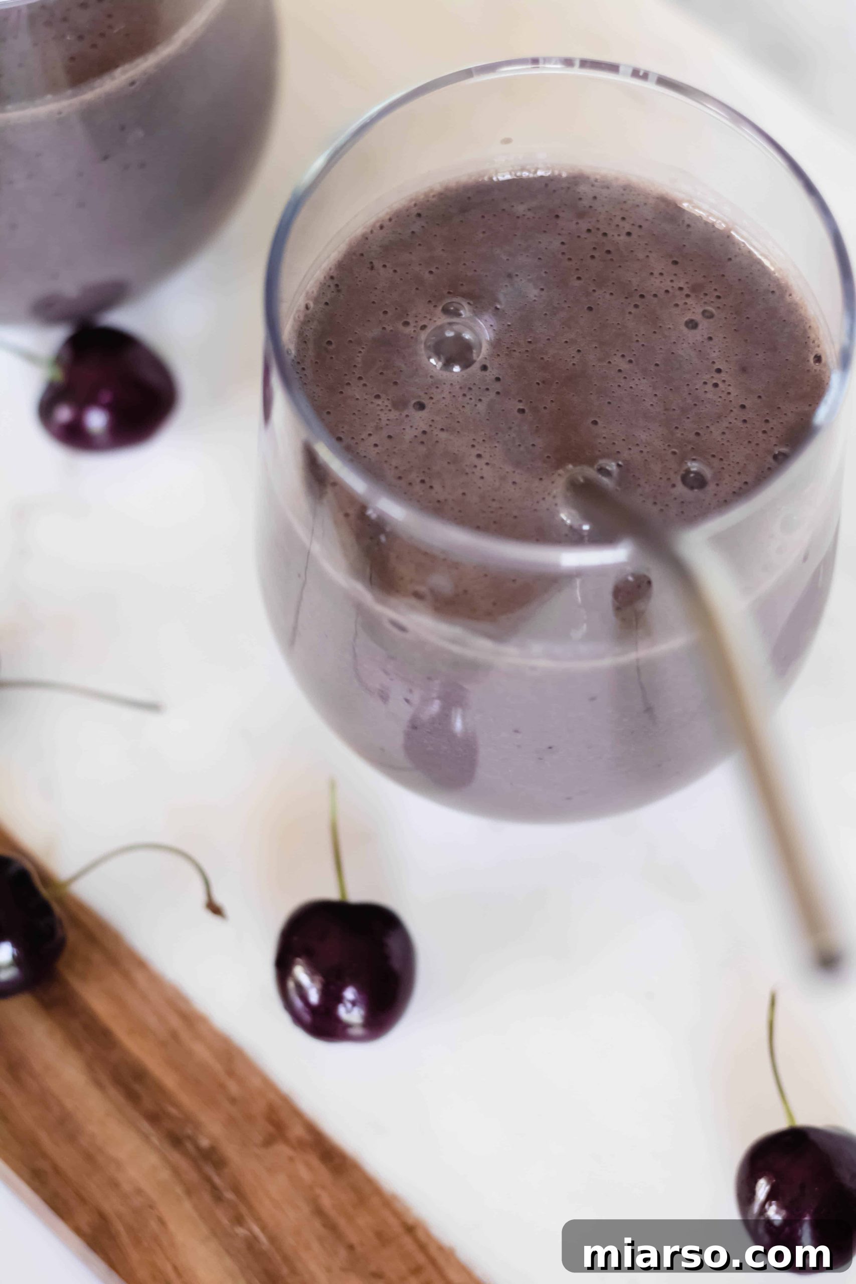 Two glasses of Vegan High protein chocolate smoothie garnished with fresh cherries