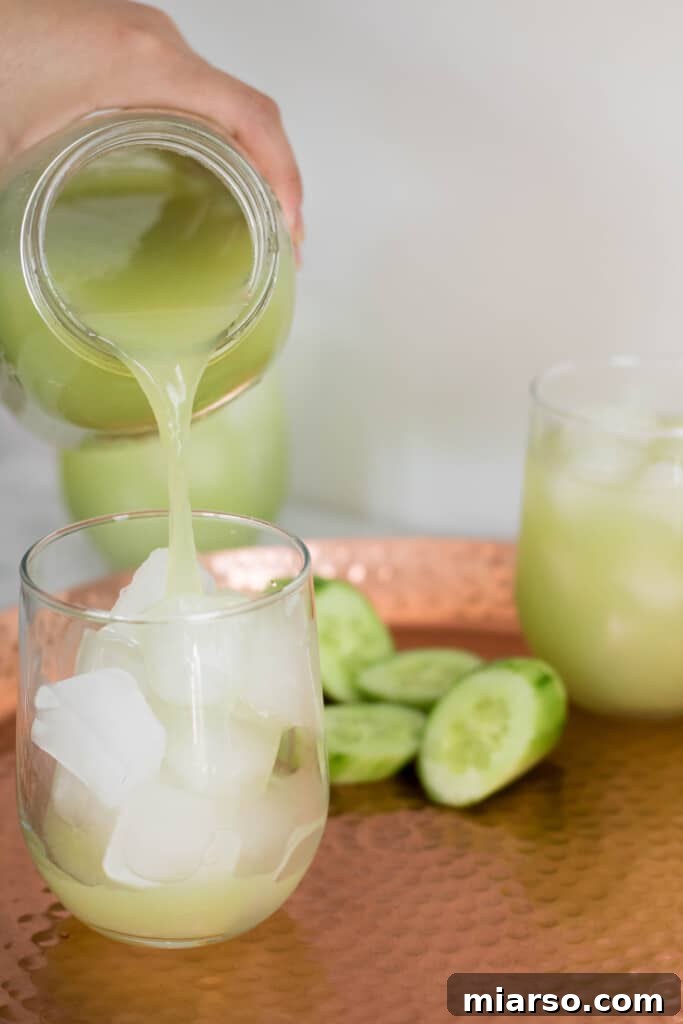 Pouring freshly made cucumber grape lemon cooler into a glass with ice.