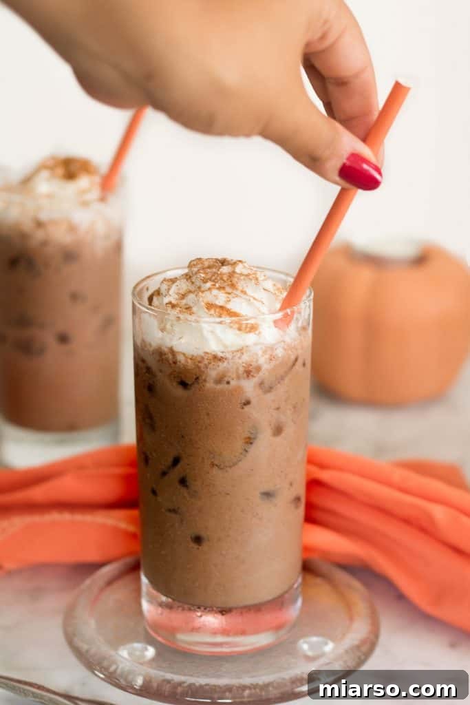 The Ultimate Vegan Iced Pumpkin Spice Hot Chocolate 4 A glass of Iced Vegan Pumpkin Spice Hot Chocolate topped with vegan whipped cream.