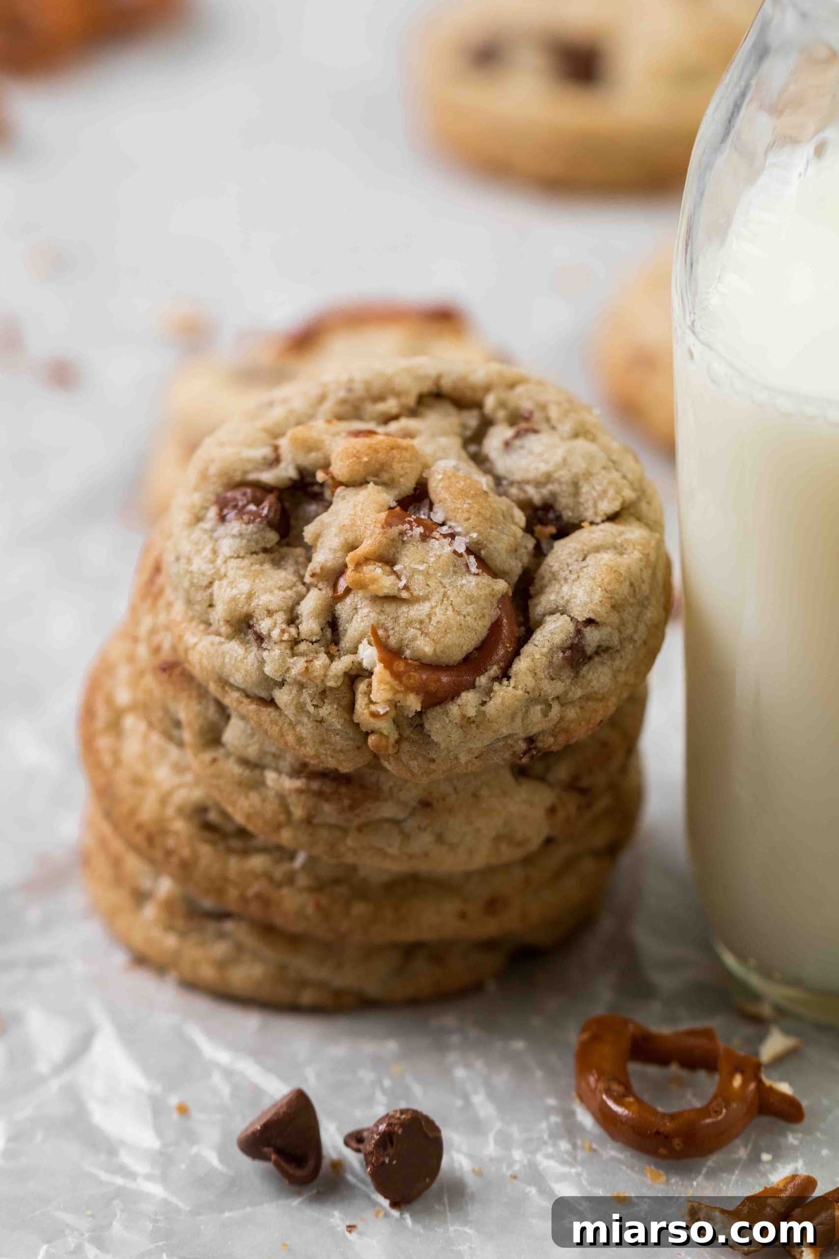 A stack of perfectly baked pretzel chocolate chip cookies, golden brown with melted chocolate chips and visible pretzel pieces.