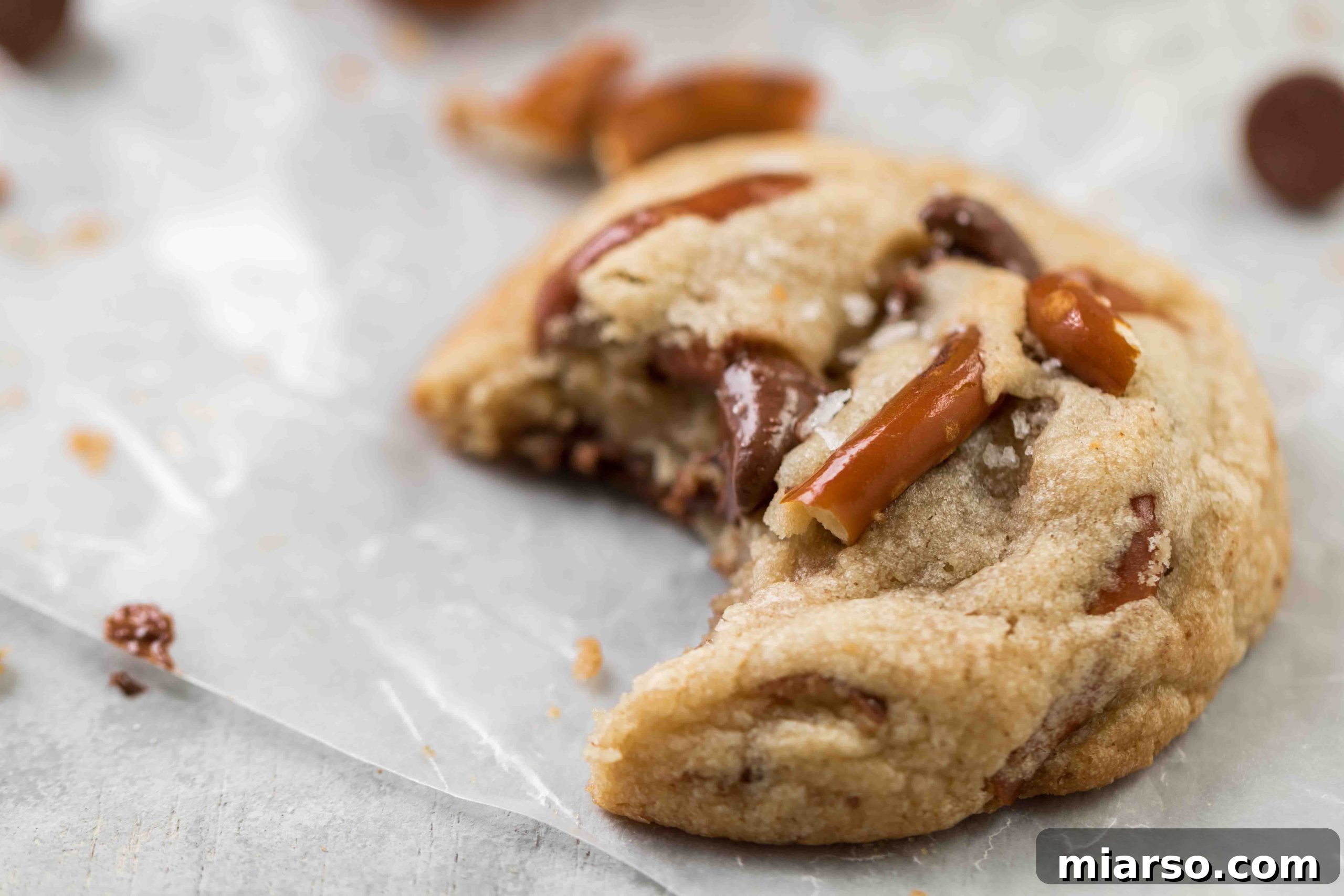 Close-up shot of a single pretzel chocolate chip cookie, showcasing its golden-brown exterior, visible pretzel bits, and melty chocolate.