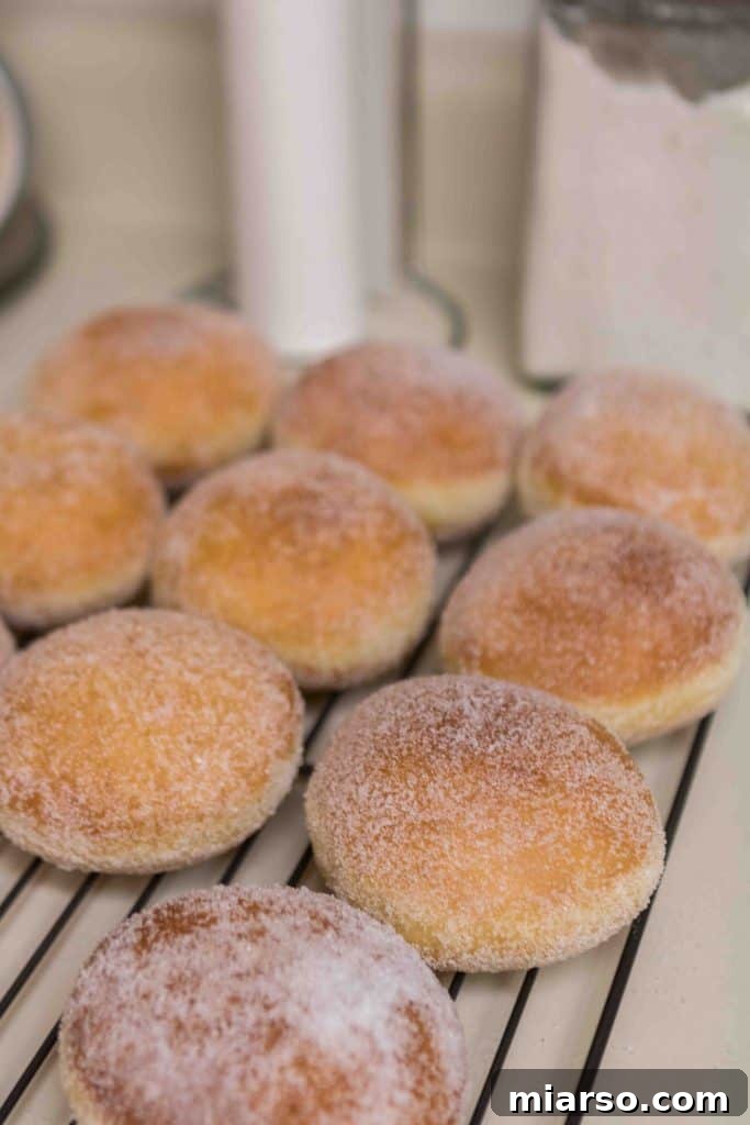 Donuts being coated with granulated sugar after frying for a sweet finish