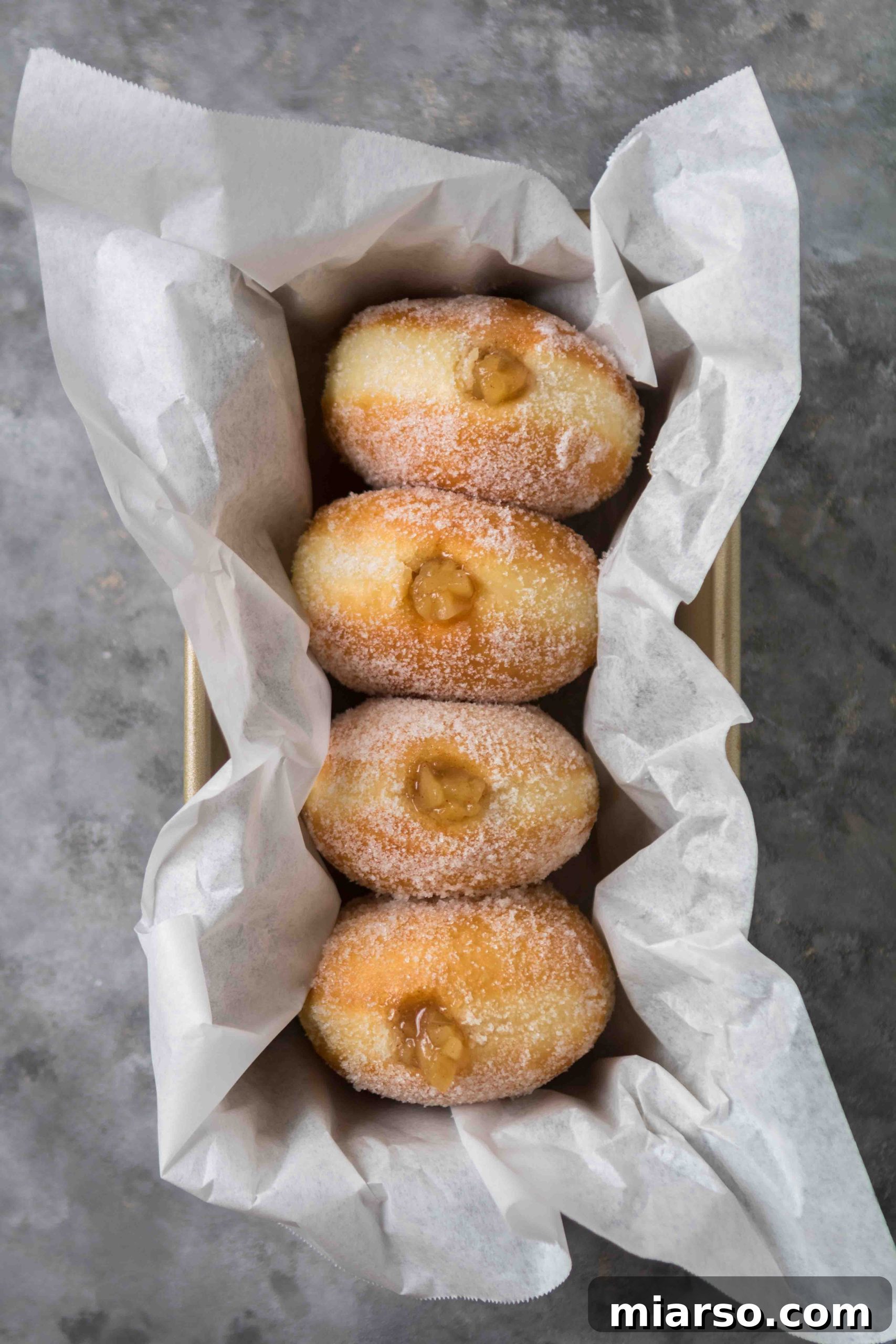 Delicious apple stuffed donuts piled high, showcasing their golden brown crust and generous filling