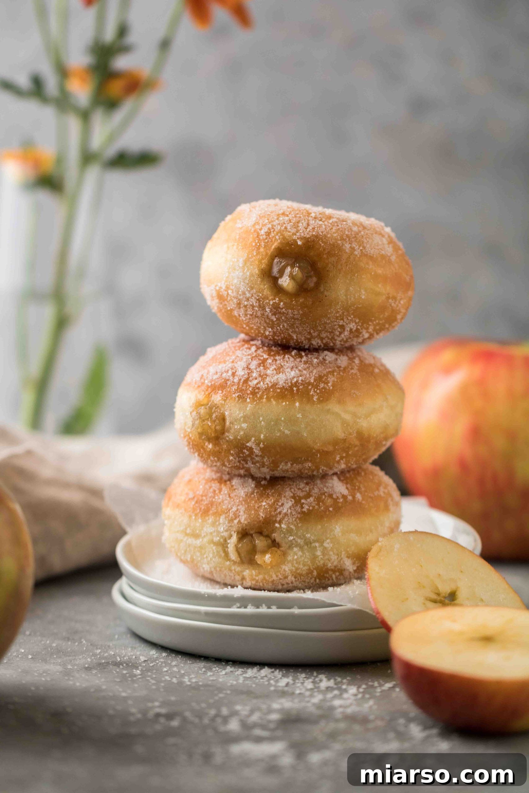 A plate of warm, cinnamon-dusted apple filled donuts, tempting for fall