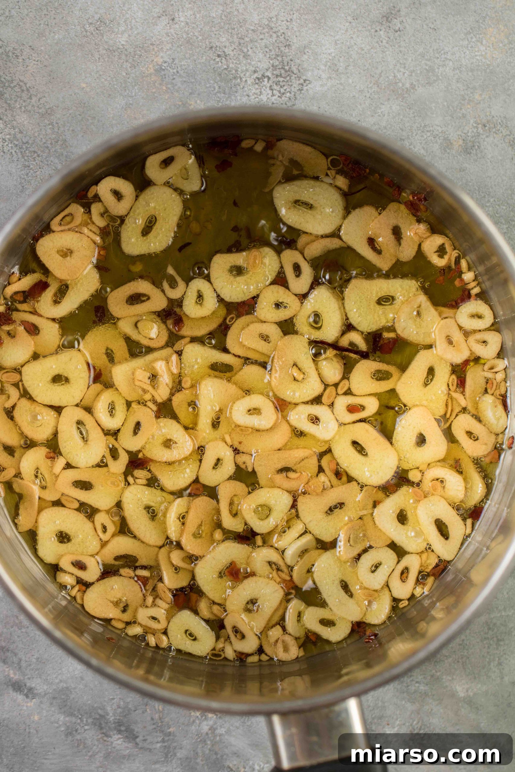 Aromatic Garlic and Olive Oil Spaghetti 4 Detail view of thinly sliced garlic sizzling and caramelizing in olive oil in a saucepan, a crucial step for infusing flavor.