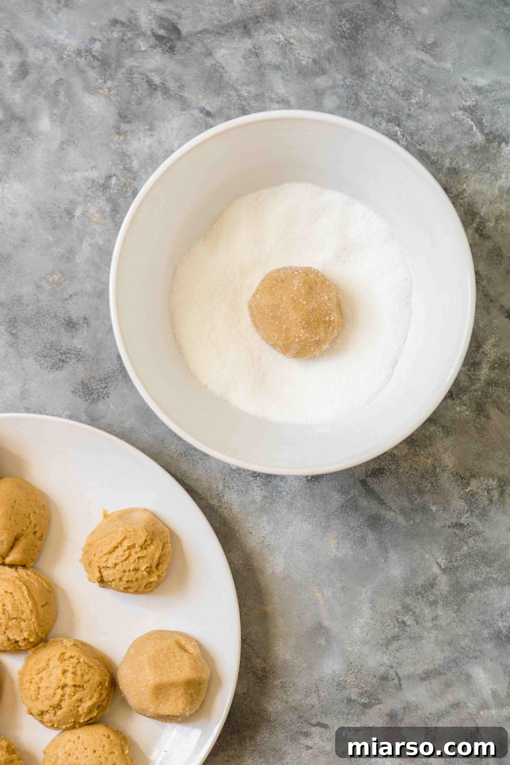 Brown sugar cookie dough balls rolled in sugar, ready for baking.