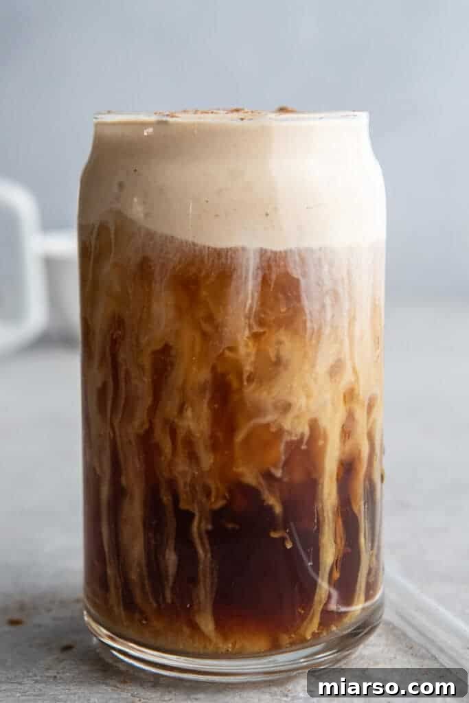 Fall's Ultimate Starbucks Pumpkin Cream Cold Brew 2 A refreshing glass of homemade Pumpkin Cream Cold Brew, garnished with cinnamon sticks and a sprinkle of pumpkin spice.