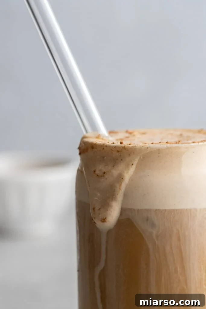 Fall's Ultimate Starbucks Pumpkin Cream Cold Brew 8 A close-up shot of a perfectly layered pumpkin cold foam cold brew, showing the frothy cream topping.